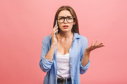 Oh No! Really? Shocked Young Woman Using Mobile Phone, Wearing Casual, Isolated On Pink Background.