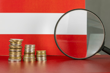 Magnifying glass and coins in front of Austria flag, country economy concept