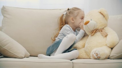 4k video of cute little girl sharing secrets with her teddy bear and smiling.