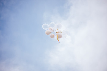 A large bunch of white balloons flying into the sky filled with helium