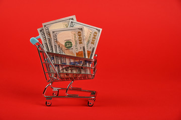 US dollar banknotes in shopping cart over red