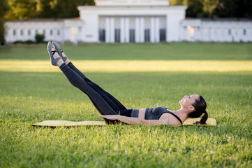 Beautiful young woman lying on a yellow mattress doing pilates or yoga, the hundred intermediate exercises