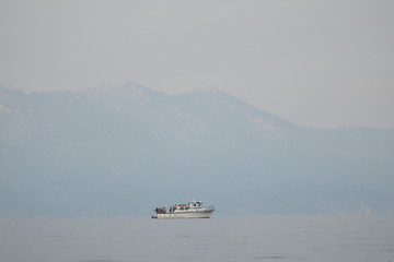 Smokey Skies Over Lake Tahoe with a Fishing Boat in the Foreground and Surrounding Western Sierras...
