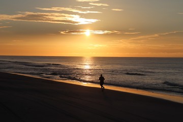 Fototapeta na wymiar silhouette of a man jogging on the beach