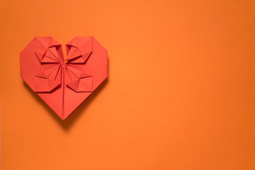 red origami paper heart on orange background, valentines day greeting card