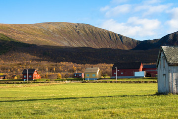 small town, with sevral houses in front of a mountain Andøya North norway grass houses