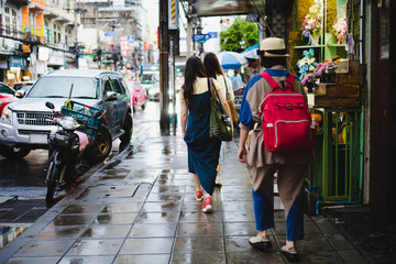 Obraz premium Group of young Asian woman walking on local wet street after raining stop in bangkok, Urban local street atmosphere. 