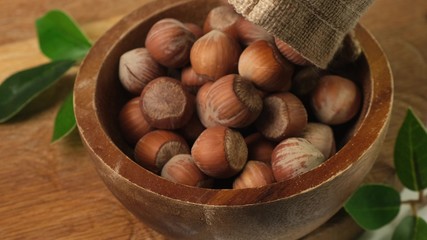 Hazelnuts are poured into a brown wooden bowl. Close up