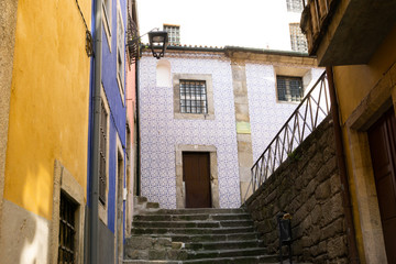 stairs of a narrow street with buildings with the facade of tiles with colored borders