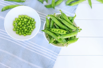 ripe sweet peas in a bowl on the table close-up. peeled green peas and pods of green sweet peas top...