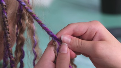 female hands with weave a braid out of hair at the hairdresser closeup