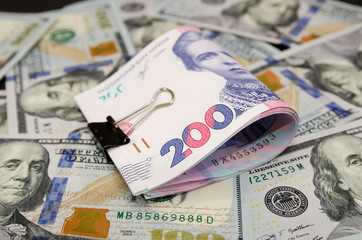 squeezed by a clip of 200 hryvnia against a background of dollars. Close-up.