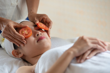 Obraz na płótnie Canvas Beautiful Asian woman relax and lying on massage bed with fresh tomatoes mask in spa salon