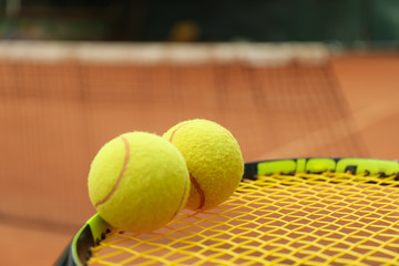 Tennis racquet with tennis balls against clay court