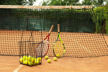 Rackets and tennis balls against net on clay court