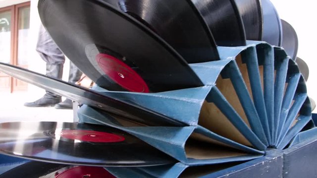 Vinyl records are folded as a set in a cardboard stand. Black discs with red labels in the center. The packaging is blue.
