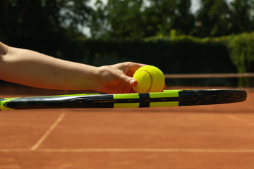 Woman hold racket and tennis ball on clay court