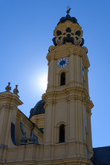 Fototapeta premium Munich, Germany: Clock tower at baroque Theatine church at Odeonsplatz in the city of Munich
