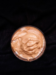Cream foam of Dalgona Coffee in close-up isolated on dark background.