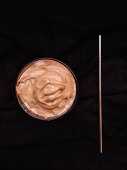Foam of Dalgona Coffee with stainless straw isolated on dark background.