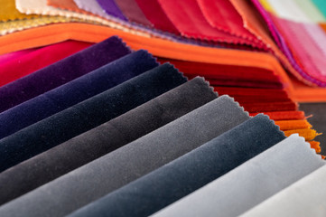 Gradient colored luxury velvet samples folded in rows and placed in a pile on a table