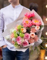 Flower shop. Beautiful bouquet of mixed flowers in man hands. The work of the florist at a flower shop. Delicate bright color. Fresh cut flower.