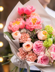Flower shop. Beautiful bouquet of mixed flowers in man hands. The work of the florist at a flower shop. Delicate bright color. Fresh cut flower.