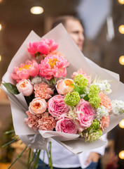 Flower shop. Beautiful bouquet of mixed flowers in man hands. The work of the florist at a flower shop. Delicate bright color. Fresh cut flower.