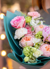 Fresh beautiful flower. Woman holding a big delicate flower bouquet of roses, peony, freesia and others wrapped in green paper.