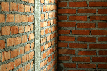 Orange brick wall with cement is formed with reinforced concrete columns to increase their strength.