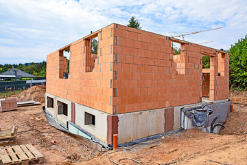 house under construction with cellar and red wall stones to built the ground floor