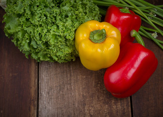 Curly green kale and bell peppers on a rustic wooden table