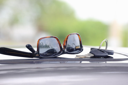 Closeup of sunglasses and car keys against a natural green background