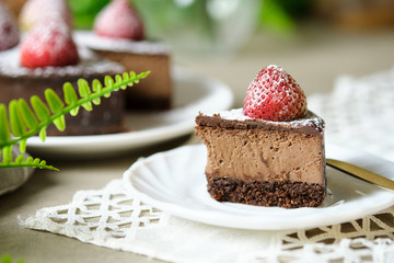 Mousse chocolate cake with strawberry and icing powder sugar. set on cafe table.