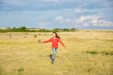 A girl with long hair runs towards the field in the summer.