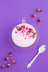 Top view of rose moon milk in glass cup on the violet surface. Location vertical.