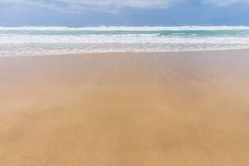 View of the ocean waves, sandy beach and sky.