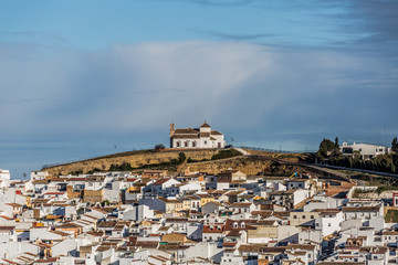Obraz premium Church on a hill and white houses around in the village of Antequera, wonderful day with a blue sky in the province of Malaga Spain