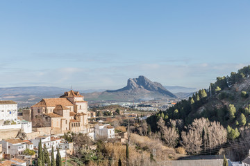 Partial urban landscape of the city of Antequera, a hill with arid vegetation with the Peña de los Enamorados or The Lovers' Rock in the background, sunny day in the province of Malaga, Spain