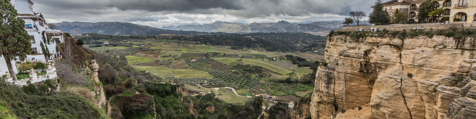 Fototapeta na wymiar Canyon or Tajo de Ronda over the Guadalevin river, the Ronda city with its buildings on the plateau, cloudy day with gray clouds in the province of Malaga Spain