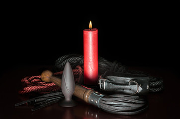 red wax candle with fire and leather whip with rope for tying
