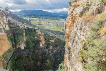 Fototapeta na wymiar Canyon (Tajo de Ronda) with a valley in the background with cultivated areas seen from the city of Ronda on a wonderful and sunny day in the province of Malaga Spain