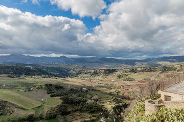 Valley of Ronda with farmland and mountains in the background on a wonderful sunny day with a blue sky and abundant white clouds in the province of Malaga Spain
