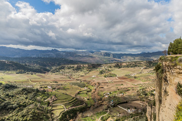 Panoramic view of the valley of Ronda with farmland and mountains in the background, sunny day and the abundant gray clouds in the province of Malaga, Spain