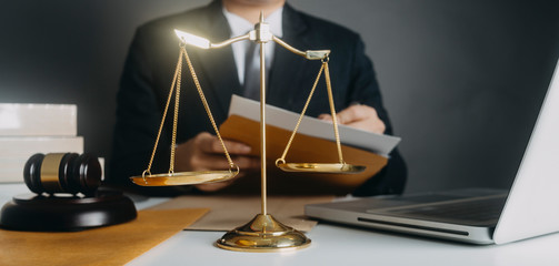 Justice and law concept.Male judge in a courtroom with the gavel, working with, computer and docking keyboard, eyeglasses, on table in morning light