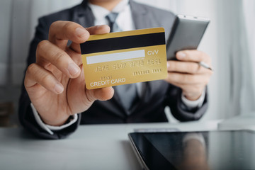 businesswoman hand using smart phone, tablet payments and holding credit card online shopping, omni channel, digital tablet docking keyboard computer at office in sun light
