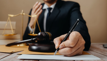 Justice and law concept.Male judge in a courtroom with the gavel, working with, computer and docking keyboard, eyeglasses, on table in morning light