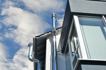 Edelstahl-Schornsteinanlage an einem modernen kombinierten Wohn-Gewerbe-Geb&auml;ude mit Imbissstube