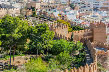 Aerial view of the Alcazaba of Almeria with its towers, walls, gardens with trees and green vegetation, with a cityscape in the background, sunny day in the municipality of Andalucia, Spain
