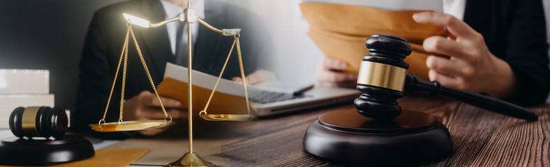 Justice and law concept.Male judge in a courtroom with the gavel, working with, computer and docking keyboard, eyeglasses, on table in morning light